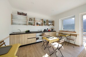 Une cuisine moderne avec des meubles en bois, un coin repas comprenant une table et des chaises, et une grande fenêtre offrant une vue sur les montagnes.