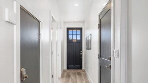 A hallway with wooden flooring, white walls, and a dark door at the end. - Freedom Village 549, Smart TV, Private Balcony, Resort Amenities and more (Washington)