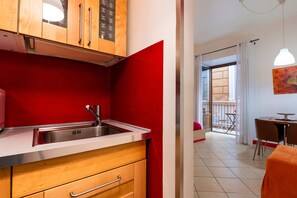 Une cuisine avec des meubles en bois, un Ă©vier en acier inoxydable et un mur dâaccent rouge.
