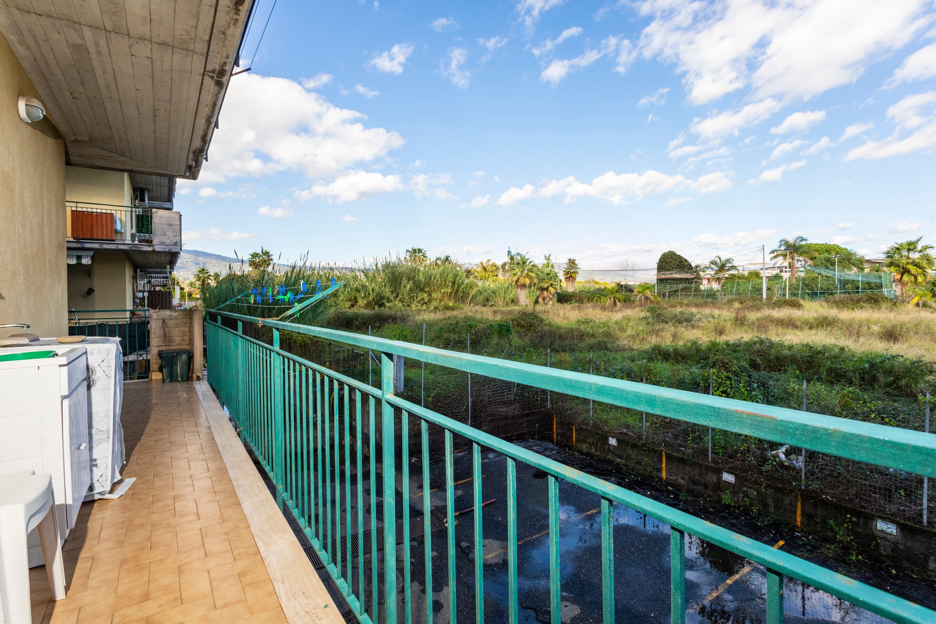 Un balcon donnant sur un cours d’eau, une structure en béton et quelques espaces verts.