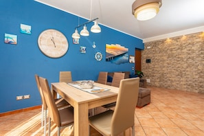 Un coin repas avec une table en bois, des chaises et une grande horloge murale.