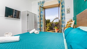 Ein Schlafzimmer mit Bett, Fernseher, Kleiderschrank und einem Balkon mit Aussicht.