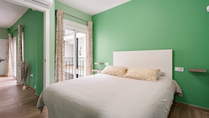 Une chambre à coucher avec un lit, des murs verts, une tête de lit blanche et des rideaux à motifs.