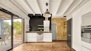 Eine moderne Küche mit Geschirrspüler, Backofen und einer Wand mit Steinverkleidung.