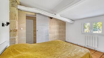 Une chambre à coucher avec un lit, une porte, une fenêtre et un mur en pierre.