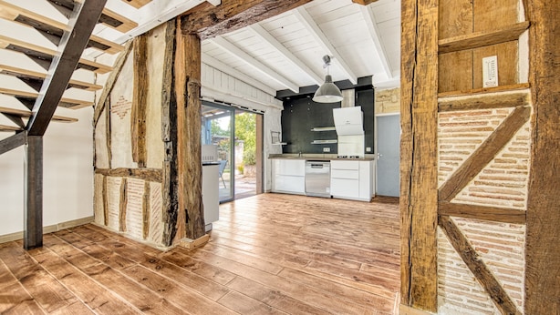 Eine geräumige Küche mit Holzbalken, einem Geschirrspüler und einem großen Fenster.
