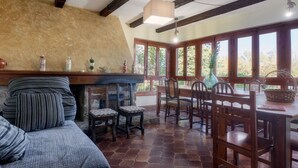 A rustic room with a fireplace, wooden furniture, and large windows.