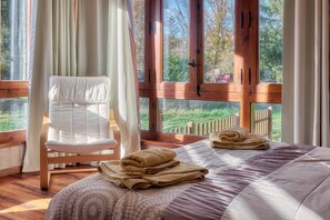 Een slaapkamer met een bed, een stoel en uitzicht op de omgeving.