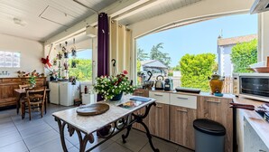 Una cocina con mesa, armarios y vistas al exterior.