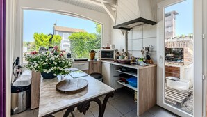 Una cocina con un ventanal grande, una mesa de madera y vistas a un edificio de ladrillo.
