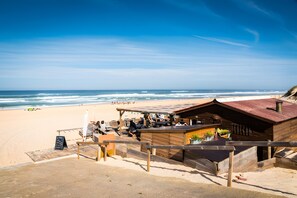 A beachside wooden structure with a covered seating area, a chalkboard sign, and a view of the ocean. - My Pied-à-Terre Near the Ocean (Saint-Julien-en-Born)
