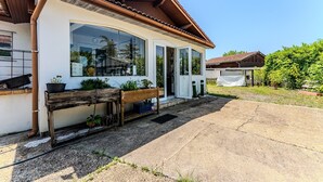 Una casa con fachada blanca, ventanas grandes y un banco de madera en el exterior.