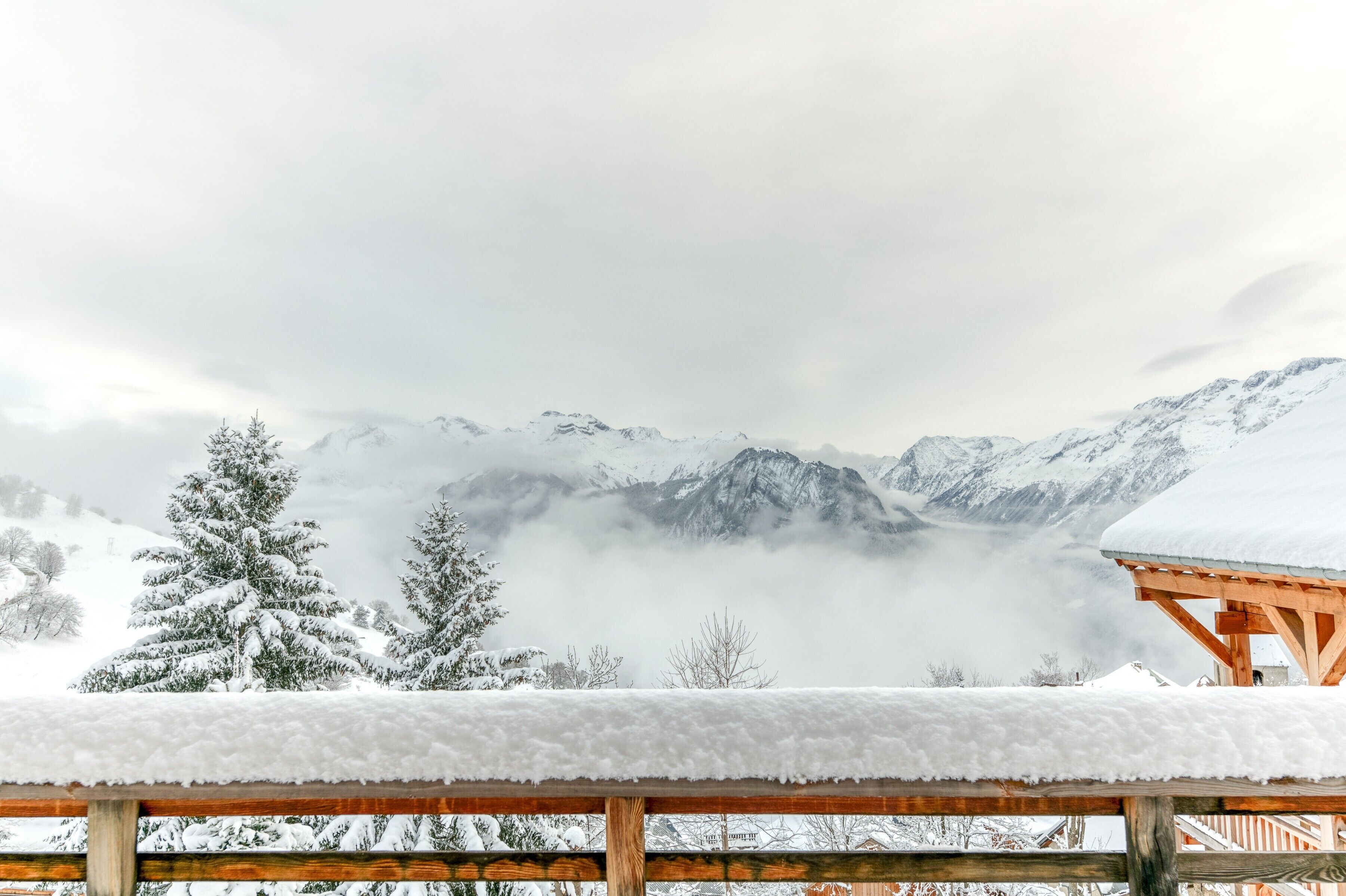 Un paysage montagneux enneigé, avec une structure en bois au premier plan.