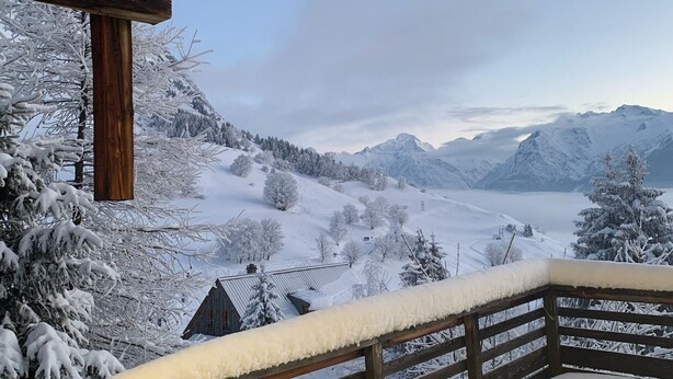 A wooden balcony with snow-covered railings overlooking a snowy mountainous landscape with a cabin. - Chalet "Belledonne" with Mountain Views, Private Terrace and Wi-Fi (Villard-Reculas)