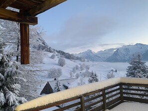 A wooden balcony with snow-covered railings overlooking a snowy mountainous landscape with a cabin. - Chalet "Belledonne" with Mountain Views, Private Terrace and Wi-Fi (Villard-Reculas)