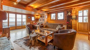 A cozy cabin interior with wooden walls, a sofa, a coffee table, and a fireplace. - Chalet "Belledonne" with Mountain Views, Private Terrace and Wi-Fi (Villard-Reculas)