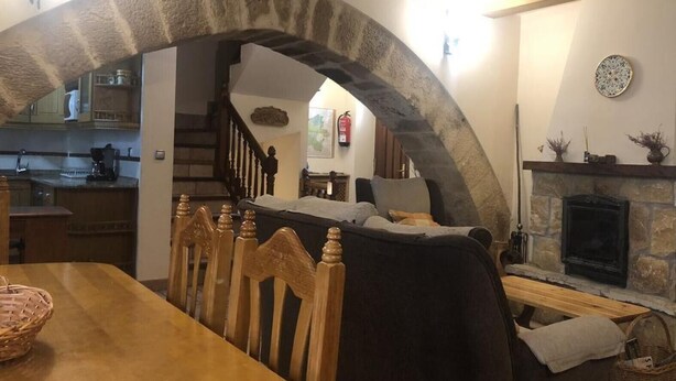 A dining area with a stone archway, a fireplace, and a kitchen visible through the archway.