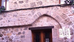 A stone building with a wooden door and a small arched window.