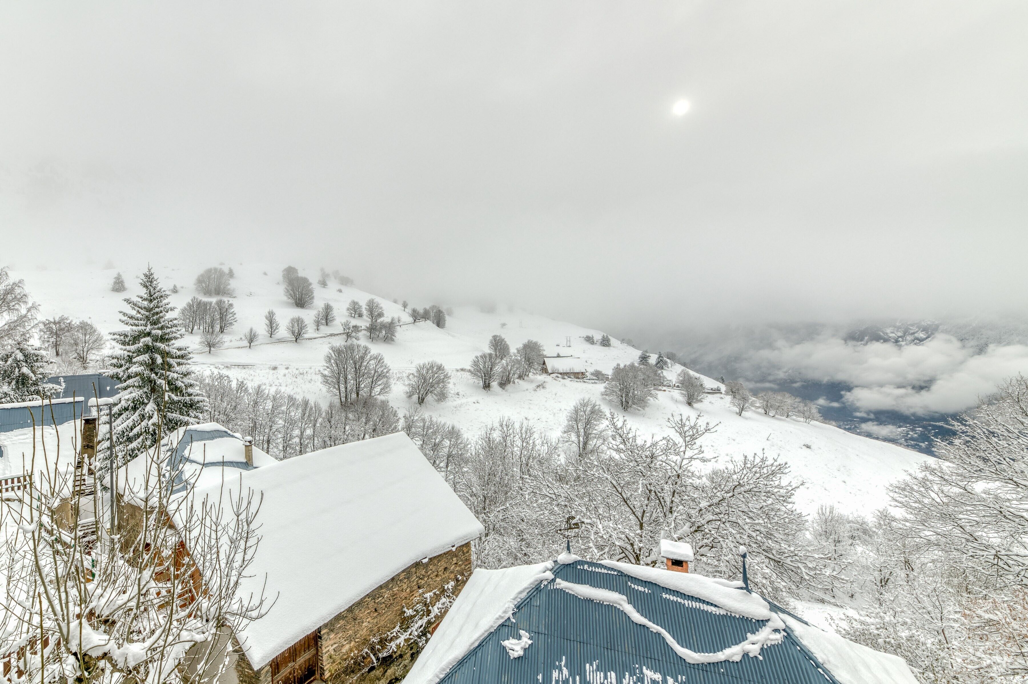 Schneebedeckte Landschaft mit Gebäuden und Bäumen.