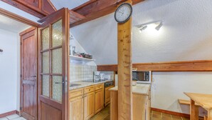 A kitchen with wooden cabinets, a microwave, a coffee maker, and a clock on the wall.
