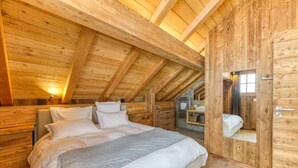 A wooden cabin bedroom with a bed, a nightstand, and a mirror. - Magnificent Apartment Le Taillefer with Mountain View, Balcony, Ski-In/Ski-Out (Villard-Reculas)