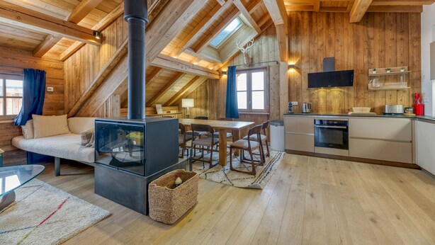 A wooden interior with a fireplace, dining area, kitchen, and a sofa. - Magnificent Apartment Le Taillefer with Mountain View, Balcony, Ski-In/Ski-Out (Villard-Reculas)