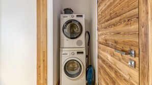 A compact laundry area with stacked washing machines and a wooden door. - Magnificent Apartment Le Taillefer with Mountain View, Balcony, Ski-In/Ski-Out (Villard-Reculas)