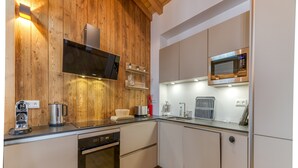 A modern kitchen with wooden walls, stainless steel appliances, and a built-in microwave. - Magnificent Apartment Le Taillefer with Mountain View, Balcony, Ski-In/Ski-Out (Villard-Reculas)