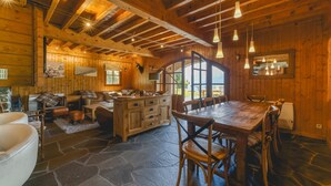Un interior rústico de madera con suelo de piedra, muebles de madera y un amplio ventanal de arco.