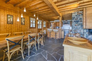 A wooden interior with a stone floor, wooden benches, and a kitchen area with stone walls. - Chalet 'Gabbro- Moderne Tout Confort' with Mountain View, Private Terrace and Wi-Fi (Villard-Reculas)