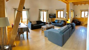 A spacious living area with wooden floors, a sofa, a coffee table, and a television. - Chalet '4 Étoiles La Saulire' with Mountain View, Shared Terrace and Wi-Fi (Villard-Reculas)