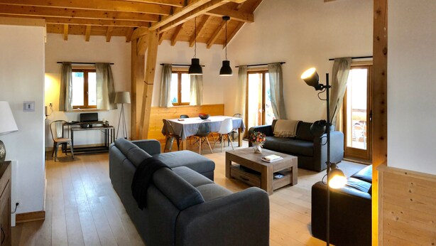 A spacious living area with a wooden ceiling, a sofa, a coffee table, a dining table with chairs, and a TV. - Chalet '4 Étoiles La Saulire' with Mountain View, Shared Terrace and Wi-Fi (Villard-Reculas)