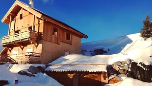 A wooden chalet with a balcony, set against a snowy landscape. - Chalet '4 Étoiles La Saulire' with Mountain View, Shared Terrace and Wi-Fi (Villard-Reculas)
