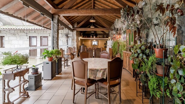 A rustic dining area with a round table, chairs, and potted plants. - Apartment 'Casa Do Caldas - Casa 4' with Shared Pool, Wi-Fi and Air Conditioning (Retorta)