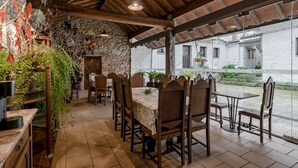 A covered dining area with wooden tables and chairs, stone walls, and potted plants. - Apartment 'Casa Do Caldas - Casa 4' with Shared Pool, Wi-Fi and Air Conditioning (Retorta)