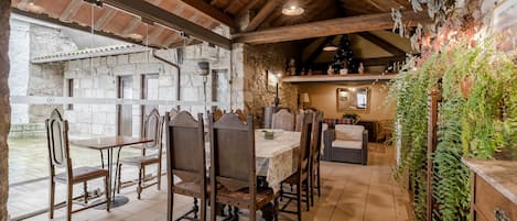 A rustic dining area with a stone wall, wooden ceiling, and a table set for four.
