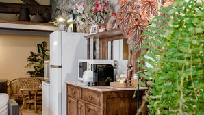 A kitchen with a refrigerator, microwave, and wooden cabinets. There is a dining area with a chair and table. - Apartment 'Casa Do Caldas - Casa 4' with Shared Pool, Wi-Fi and Air Conditioning (Retorta)