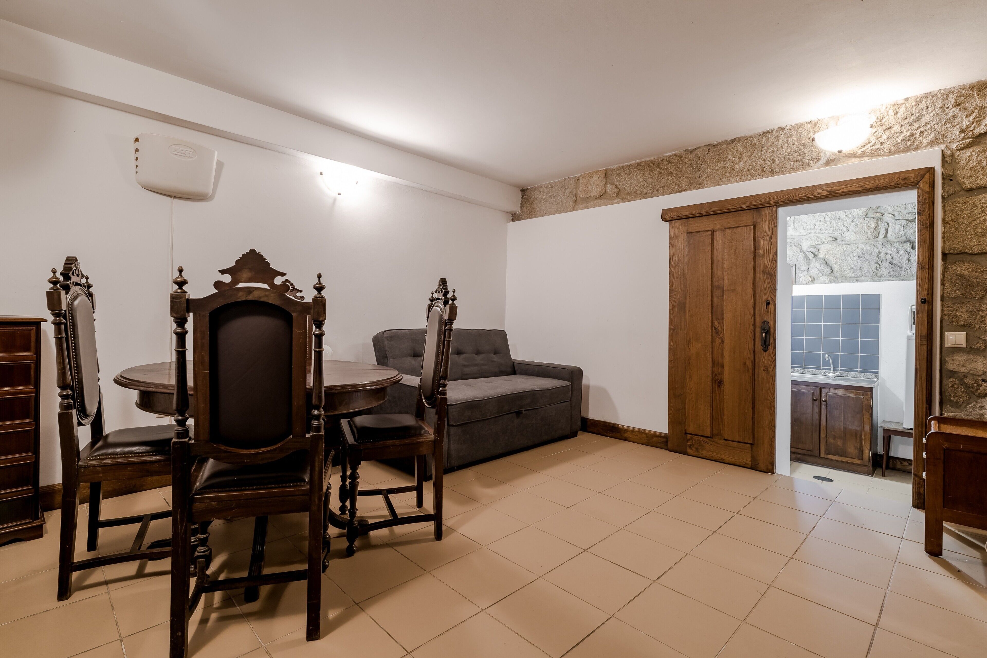 Un comedor con una mesa redonda y sillas, un sofá y una pared de piedra.