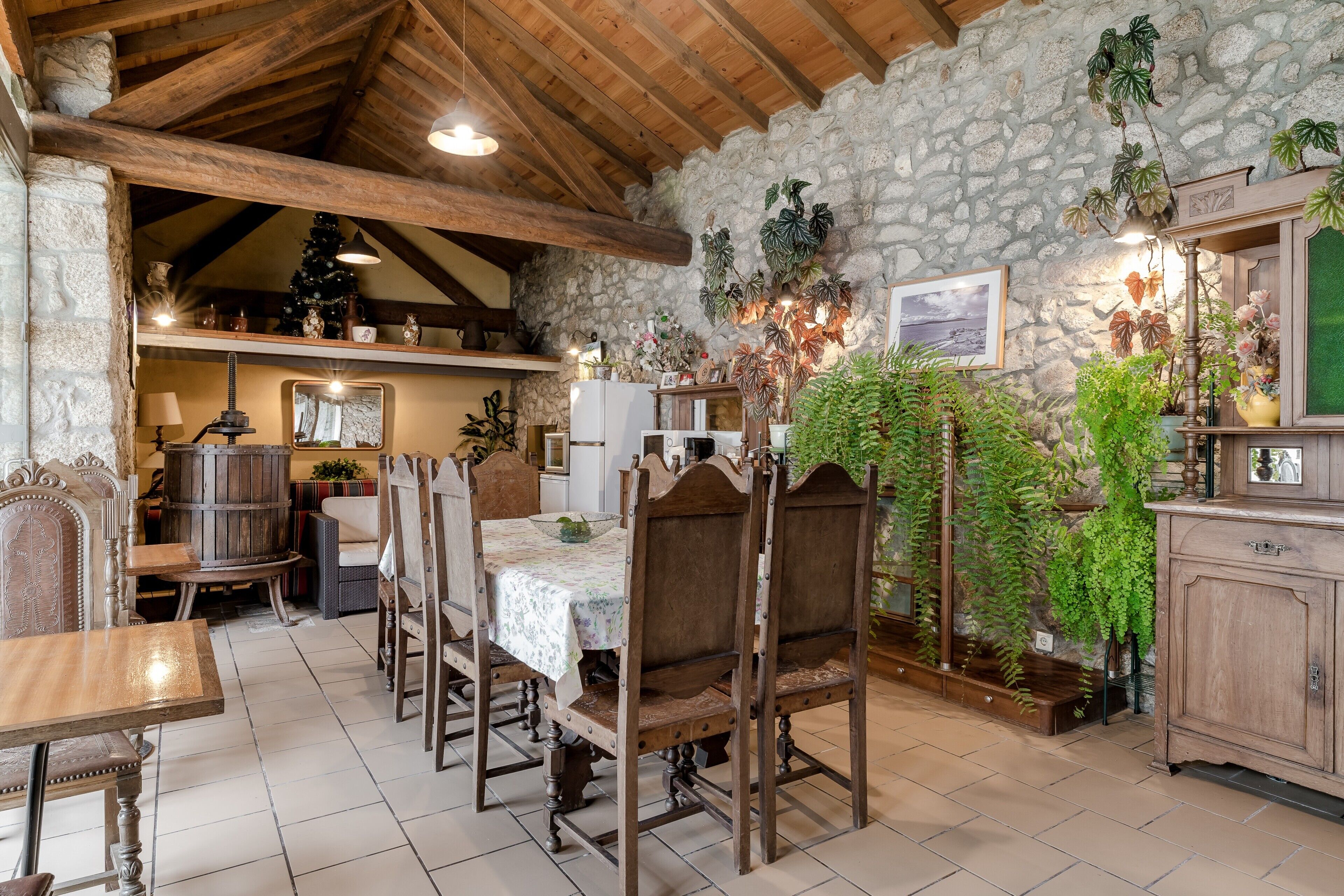 Un coin repas rustique, avec des meubles en bois, des murs en pierre et diverses plantes en pot.