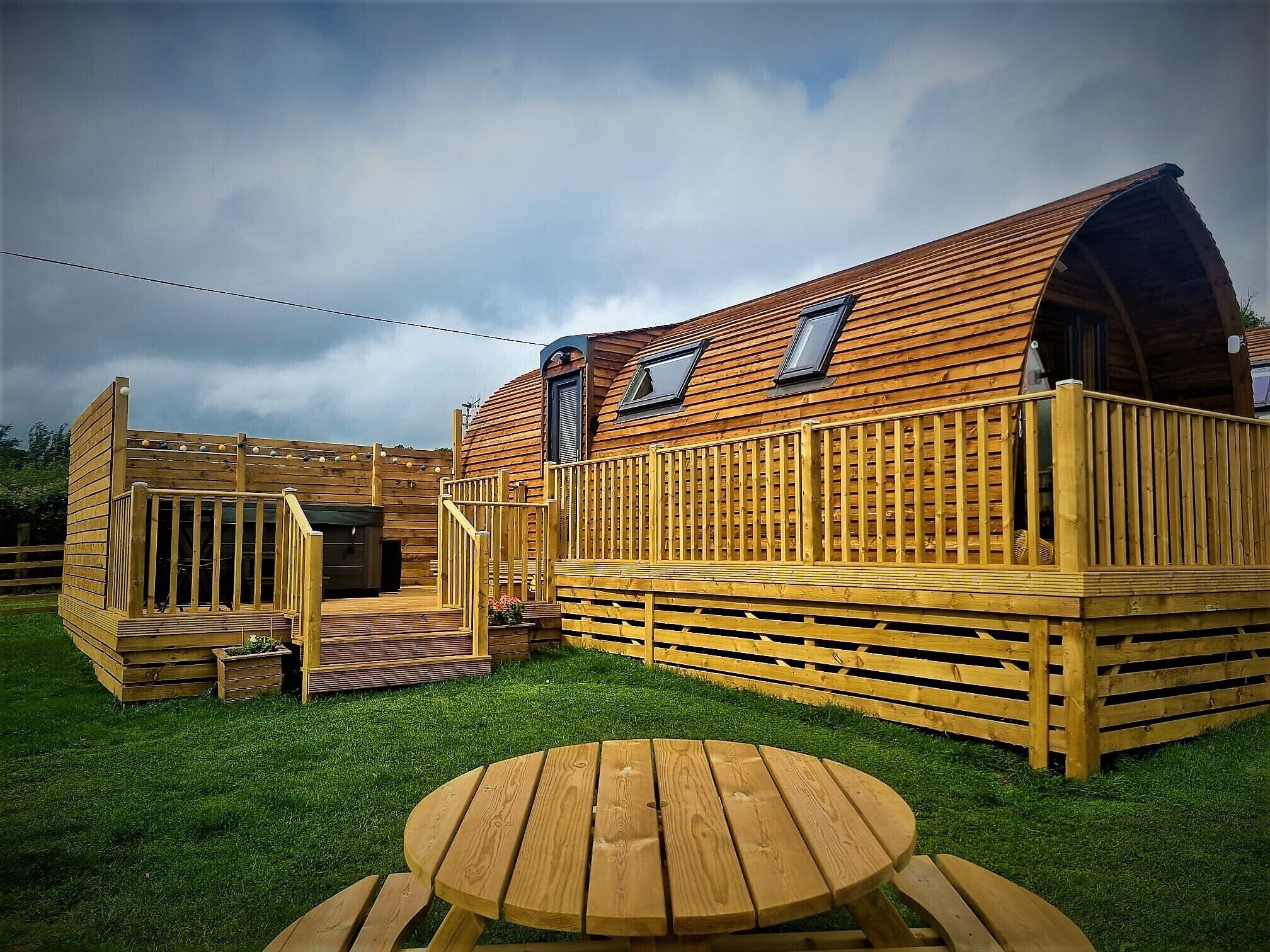Een houten hut met een terras, een klein patio en een ronde tafel.