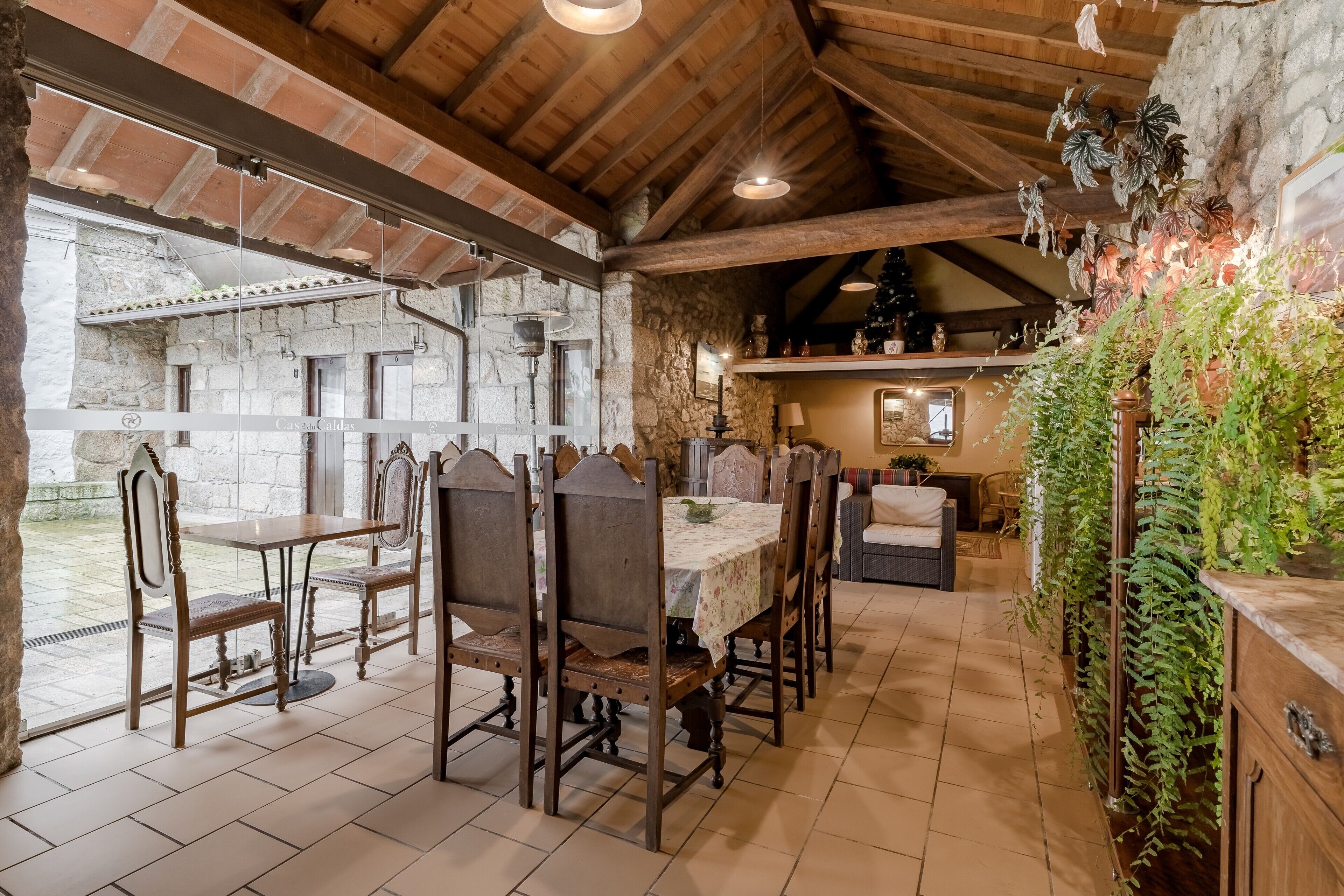 A rustic dining area with a stone wall, wooden ceiling, and a table set for four.