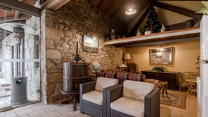 Une pièce chaleureuse aux murs de pierre, meublée de meubles en osier, avec une cheminée et un sapin de Noël.
