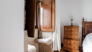 Une chambre à coucher avec une commode en bois, un lit et un escalier en pierre.