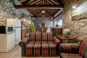 Un intérieur rustique avec des murs en pierre, des poutres en bois, un canapé à rayures, un globe terrestre et un coin cuisine.