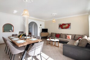 A modern living room with a dining area, a sofa set, and a TV.