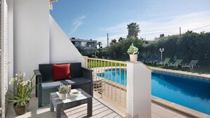 Een balkon met een zwembad, een bank en een tafel met een plant in pot.