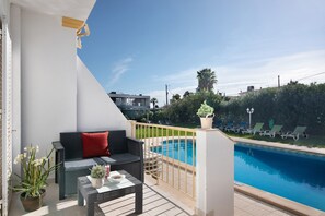 A balcony with a pool, a sofa, and a table with a potted plant.
