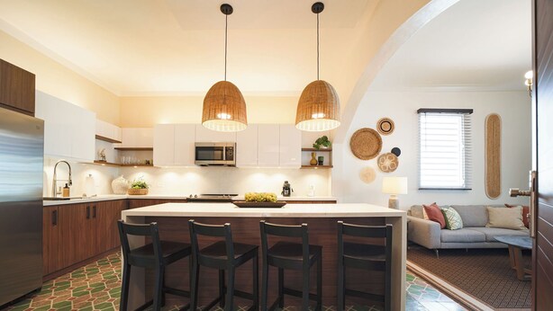 A modern kitchen with a central island, bar stools, and pendant lighting.
