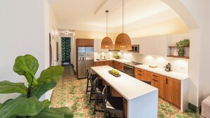 A modern kitchen with a central island, wooden cabinets, and pendant lighting.
