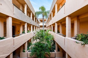 A multi-level atrium with a central palm tree, balconies, and a clear sky. - Apartment 'Casa Jakalia' with Shared Pool, Wi-Fi and Air Conditioning (Marbella)